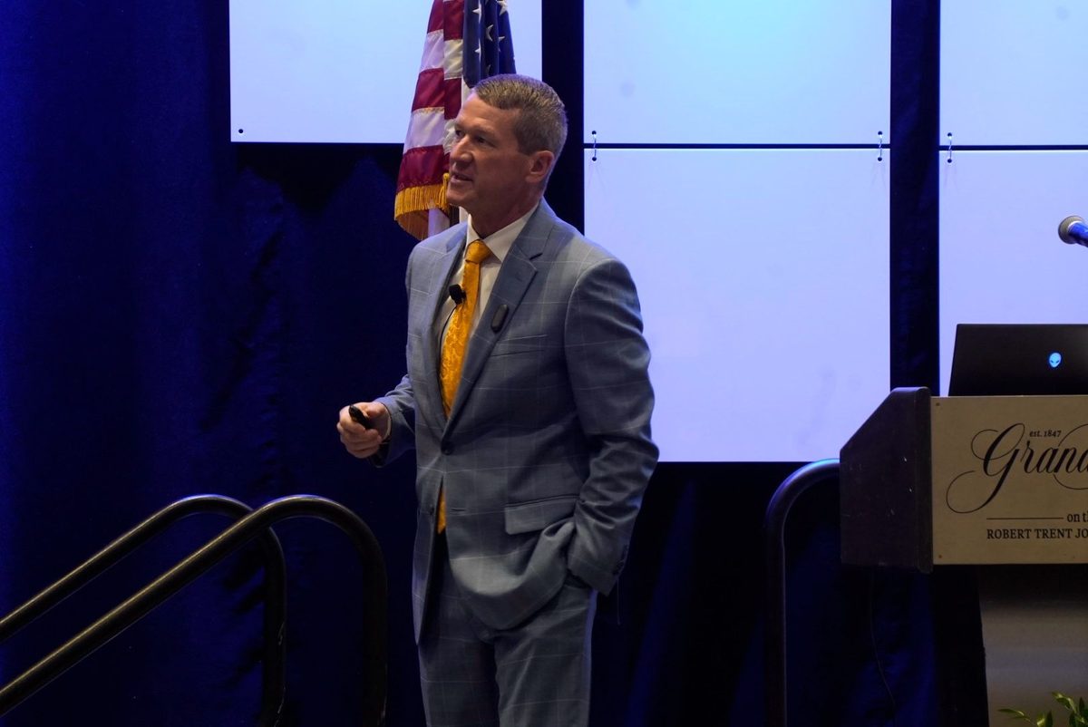 Chris Chism presenting on Practical Uses of AI at the Mississippi Business Alliance Manufacturers Council Summit, Grand Hotel podium