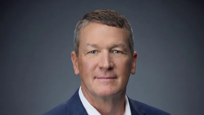 AI-generated portrait of Chris Chism in a navy blazer and white open-collar shirt, the face of his live keynote avatar